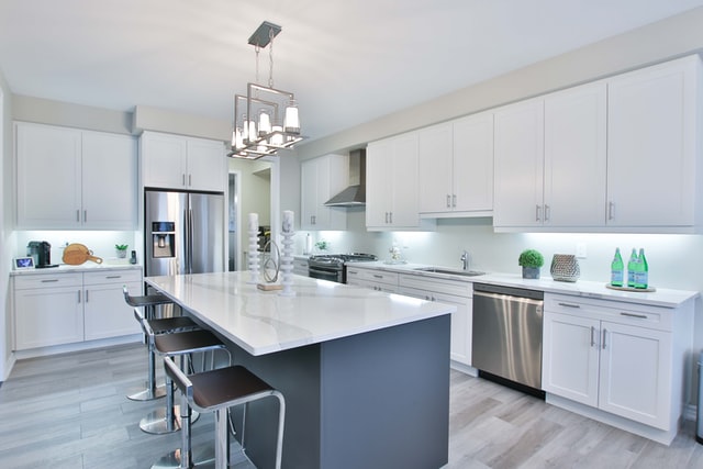 A large bright kitchen with a kitchen island and chairs in the middle