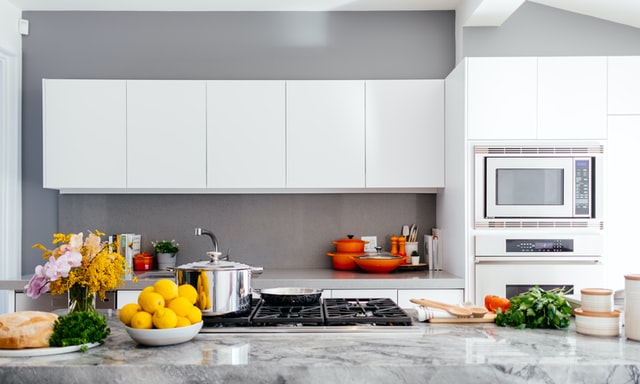 A modern white kitchen with a marble countertop