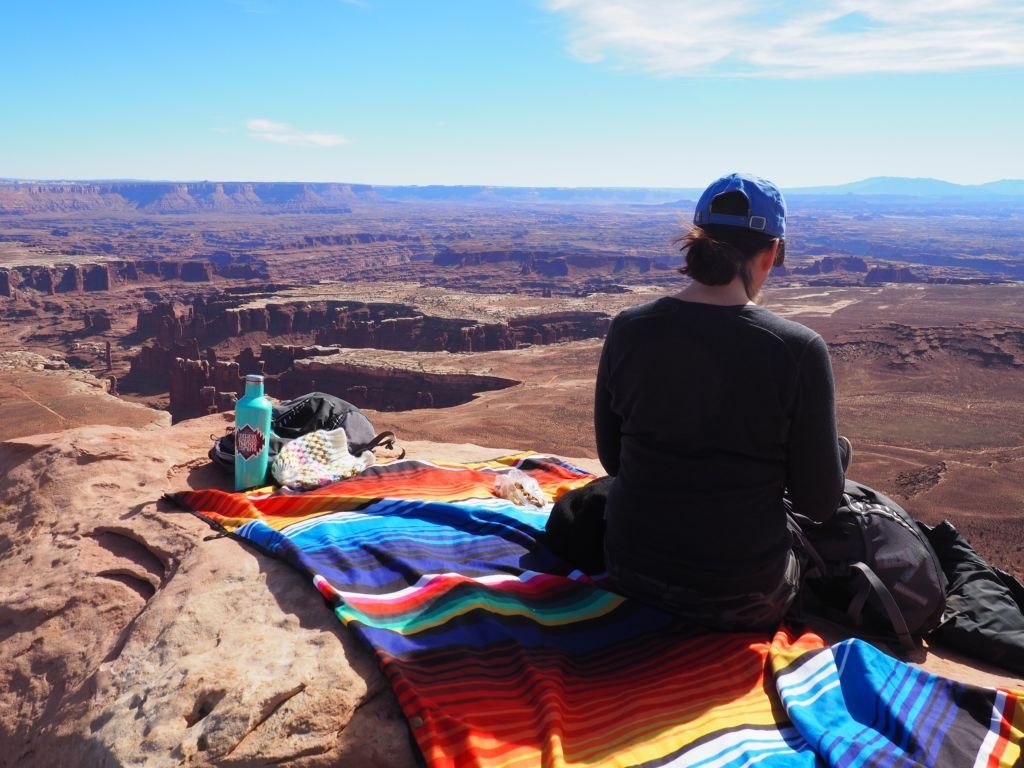 A man sitting on a Coaltree Blanket during a hike