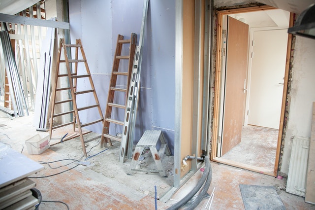 A home being renovated with tools, ladders, and step-ladders in it.