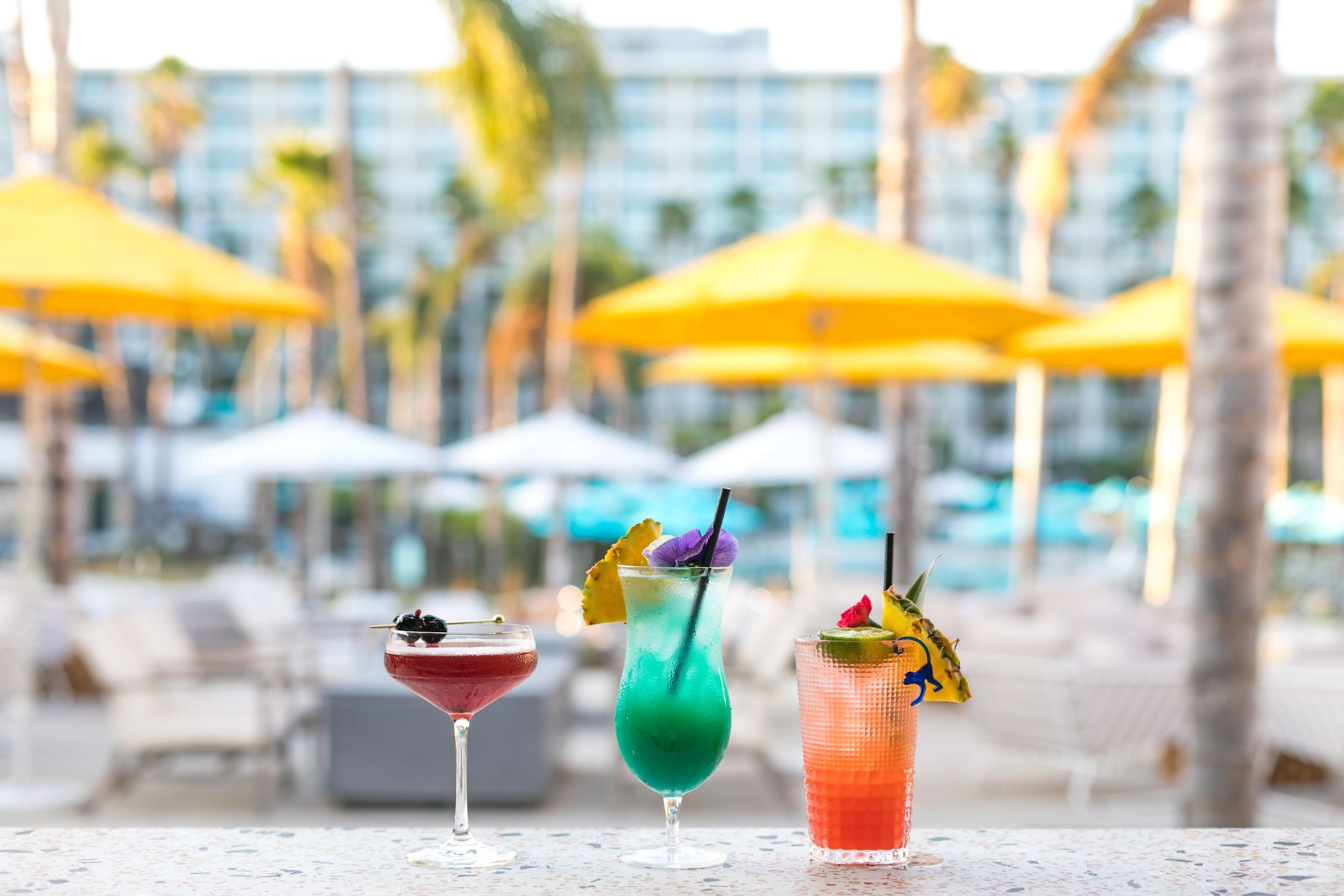 3 colorful drinks sitting on a table at a landmark resort.