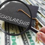 Scholarship graduation cap on money with magnifying glass