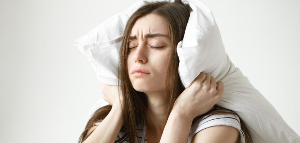 pretty-student-woman-striped-t-shirt-trying-have-some-sleep-sitting-bedroom-with-pillow-her-head-closing-eyes_343059-1447
